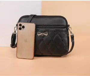 Detail shot of black quilted crossbody shoulder bag with cute heart embroidery and bow.
