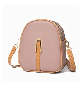 Close-up of pink mini crossbody phone bag with double zippers and elegant golden metal clasp.