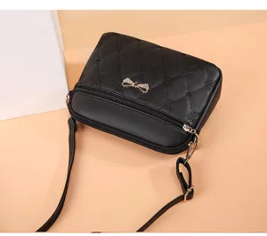 Detailed view of the black quilted crossbody bag featuring a golden bow and adjustable strap.