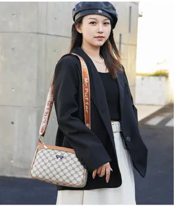 Detail view of women's fashion crossbody bag featuring monogram pattern and wide strap.