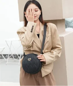 Black quilted round crossbody bag for women with wide strap and chic double heart metal hardware.