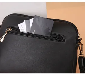 Detail view of black leather crossbody bag zipper pocket with convenient card slots.
