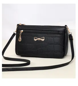 Borsa a tracolla nera in ecopelle coccodrillo con fiocco chic e scomparti con zip.