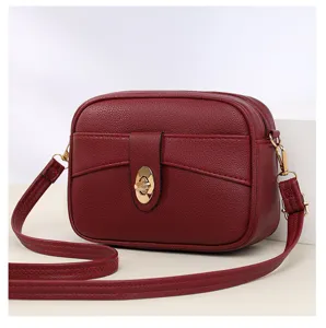 Wine red leather crossbody bag detail, featuring gold metal lock and fine stitching.