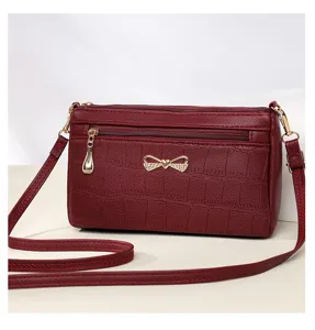 Borsa a tracolla da donna in ecopelle bordeaux con fiocco in strass chic e stampa coccodrillo.