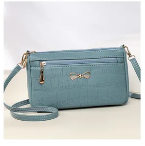 Primo piano della splendida borsa a tracolla blu con texture coccodrillo e bel fiocco.
