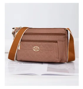 Vue détaillée du sac bandoulière en toile marron avec fermetures éclair et sangle large.