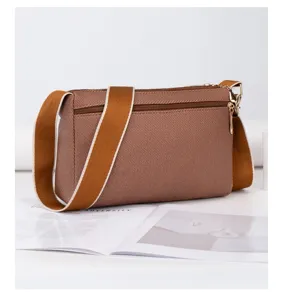 Détail de sac bandoulière en toile marron, style décontracté avec large sangle et zip doré.