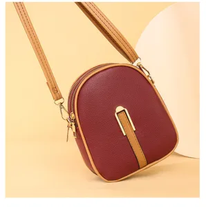 Detailed view of women small vertical crossbody phone bag, maroon PU leather, gold hardware.