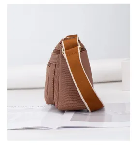 Sac bandoulière en toile marron avec sangle épaisse et multi-poches pour le quotidien.