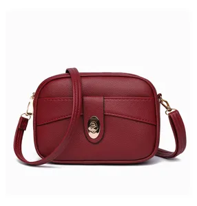 Red leather crossbody bag detail showcasing texture, gold-tone hardware and secure lock.