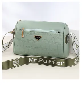 Sac à bandoulière en cuir motif crocodile vert avec fermeture éclair et large sangle.