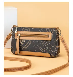 Detail view of vintage brown women's crossbody bag with geometric letter pattern and zipper.