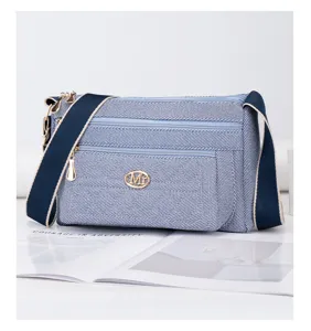 Vue détaillée du sac bandoulière en toile denim décontractée avec compartiments zippés.