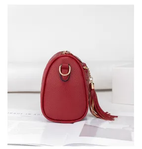 Red pebble leather pillow bag side detail with chic tassel pendant and gold hardware.