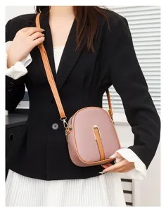 Detail view of a chic vertical crossbody phone bag in mauve pink with brown trim and clasp.