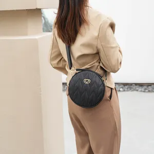 Elegantly designed black round quilted crossbody bag with wide strap and chic heart metal clasp