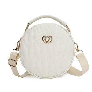 White round crossbody handbag with diamond quilting, top handle and wide strap for women.