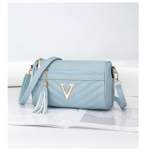 Light blue quilted chevron shoulder bag detail with elegant gold V logo and tassel pendant.