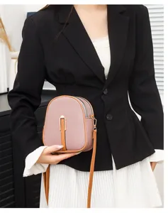 Close-up view of the vertical phone crossbody bag in pink with brown trim and gold lock detail.