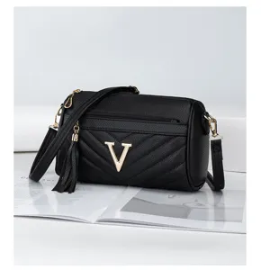 Detail view of a black quilted leather pillow bag with gold V buckle and chic tassel charm.