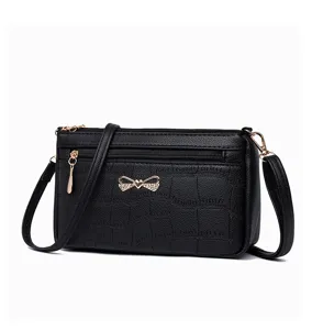 Borsa a tracolla nera con stampa coccodrillo, dettagli dorati e fiocco per stile elegante.