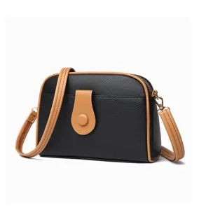 Close-up detail of the black and brown contrast shell crossbody bag showing fine texture.