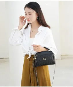Detailed view of women black quilted shoulder bag with chic tassel and heart lock design.