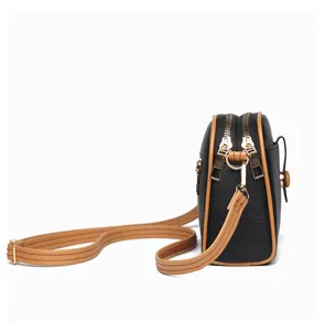 Detailed side view of black crossbody bag showing double zippers and adjustable strap.
