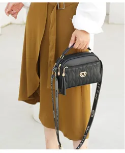Black quilted shoulder bag detail, elegant gold heart clasp and stylish tassel charm.