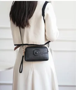 Detailed view of black faux leather mini crossbody bag with crocodile pattern and metal hardware.