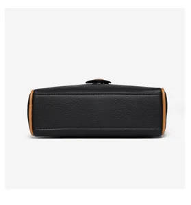 Detailed bottom view of black leather crossbody shoulder bag with tan contrast piping trim.