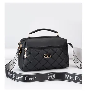 Black quilted crossbody bag for women, featuring top handle, wide strap, and chic metal plaque.