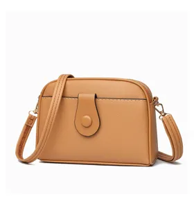 Detail view of the brown leather crossbody shell bag with front flap buckle and zipper.