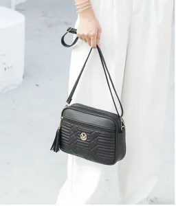 Vue détaillée du sac porté épaule noir pour femme en cuir matelassé avec pompon élégant.