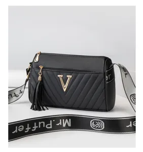 Stylish black cylindrical crossbody bag featuring metal V logo, tassel and unique strap.