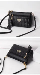 Black soft leather crossbody bag detail featuring gold hardware and elegant tassel pendant.