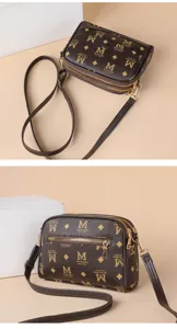 Sac bandoulière marron élégant avec monogramme, double fermeture éclair et sangle réglable.