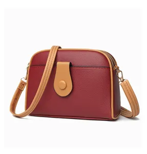 Chic women's crossbody shell bag detail, stylish red and brown leather shoulder handbag.