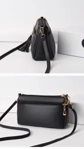 Black multi-zipper crossbody bag detail shot, soft leather messenger style with tassel charm.