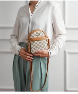 Detail view of compact vertical crossbody phone bag with monogram pattern and leather trim.