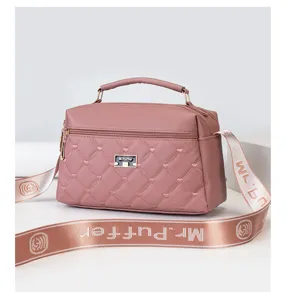 Pink quilted shoulder handbag detail, showing textured pattern, front metal logo and strap.