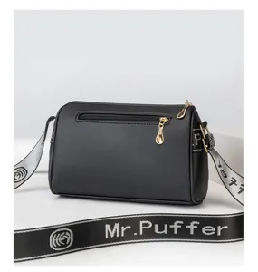 Detailed view of the black cylindrical crossbody bag featuring golden hardware and strap.