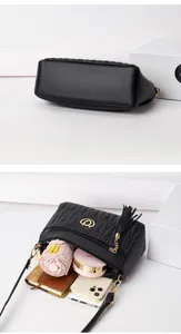Detailed view of black soft leather crossbody bag with spacious interior and tassel charm.