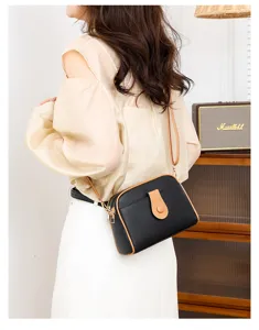 Detail view of women black leather crossbody shoulder bag with stylish brown trim