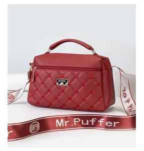 Red quilted leather shoulder bag close-up, featuring cute heart embroidery and branded strap details.