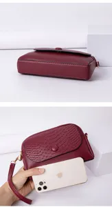 Détail de petit sac bandoulière en cuir bordeaux, avec rabat et format téléphone compact.