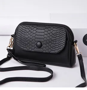 Petit sac bandoulière noir pour femme, avec un rabat texturé en peau de serpent et détails dorés.