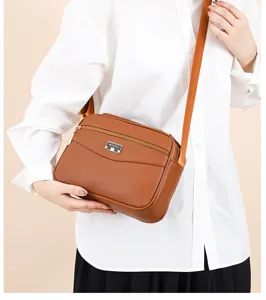 Brown PU leather crossbody bag detail view showcasing minimalist design and metal logo plate.