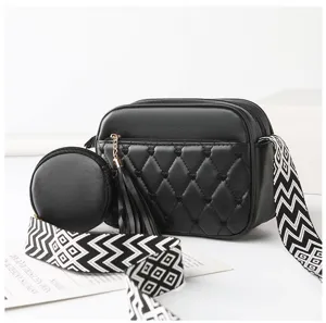 Detail view of a stylish black quilted women crossbody bag with coin purse and wide strap.